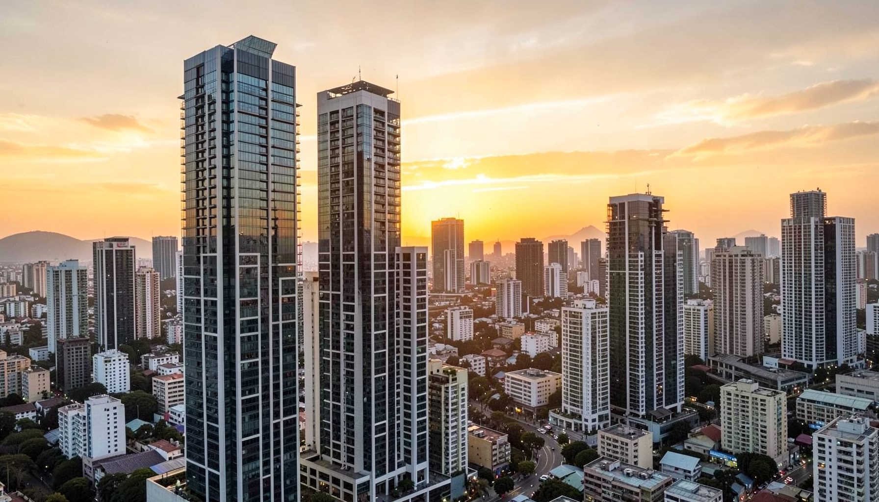 Modern high-rise buildings against a warm golden sunset sky over a growing city skyline
