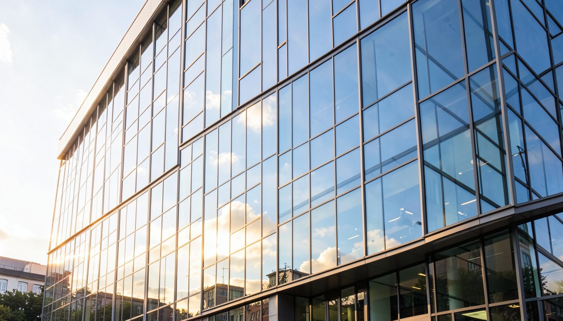 Modern office building exterior with glass facade reflecting a bright sky, warm and professional mood